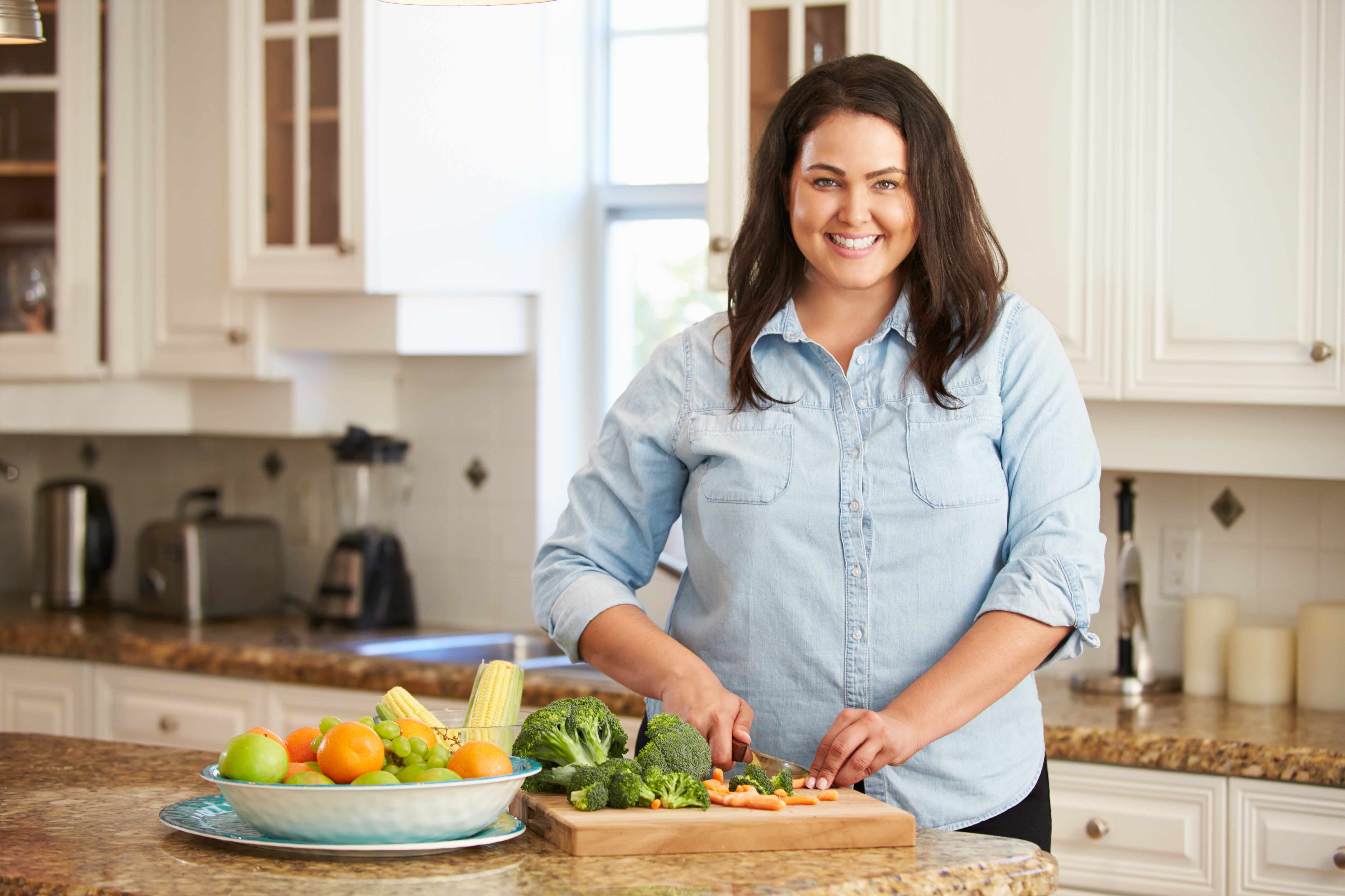 woman in kitchen cutting up healthy vegetables