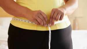 slightly overweight woman measuring waistline, stomach
