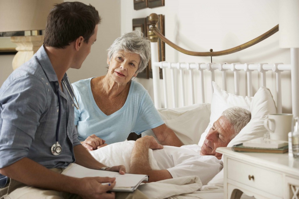 patient in bed and physician, doctor sitting with patient and family member
