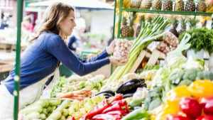 woman at a farmers market choosing vegetables