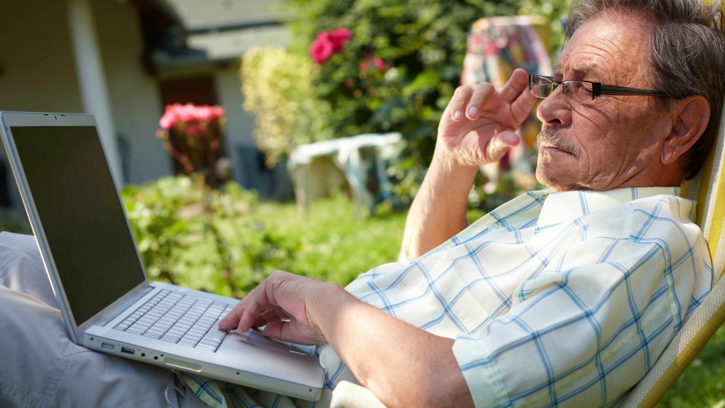 elderly man wearing glasses reading, looking at laptop computer