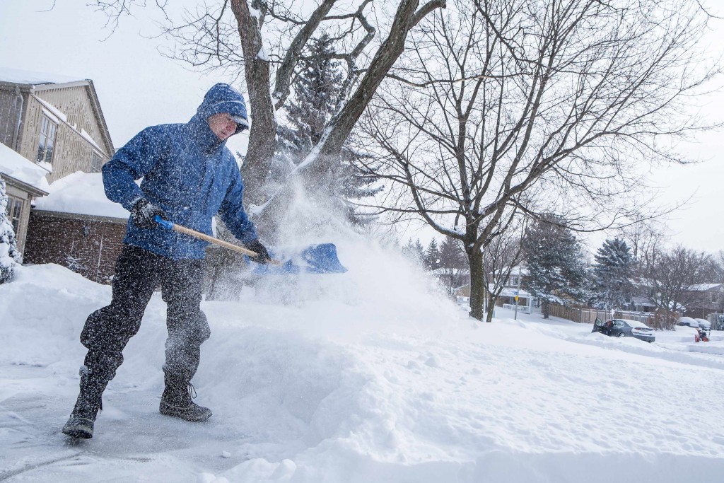 man shoveling snow from sidewalk after storm