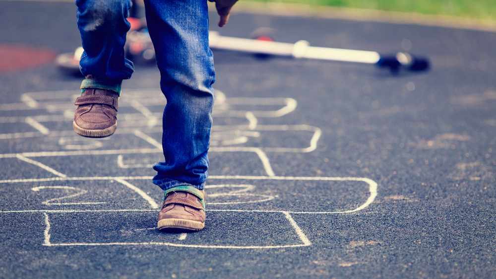 Child playing hopscotch on playground outdoors