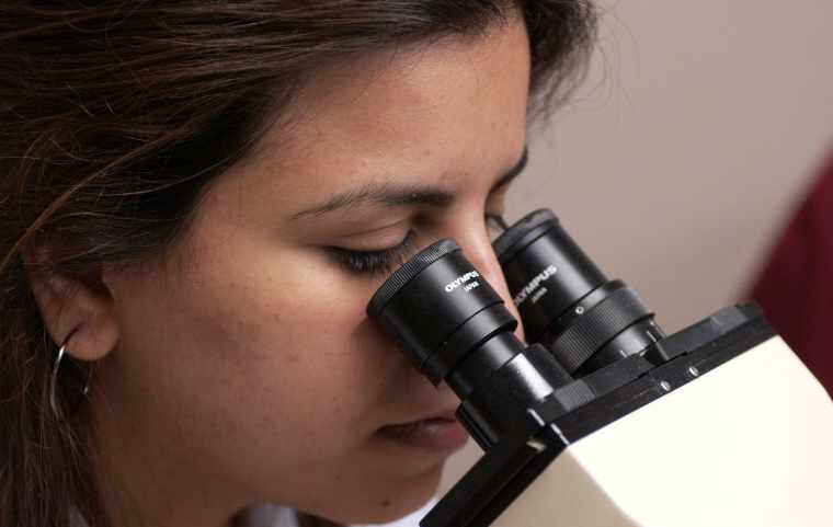 Medical student looking through microscope