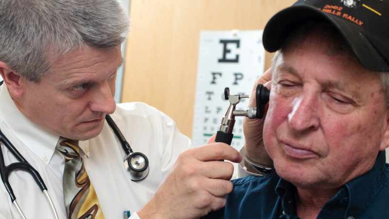 male patient with doctor checking for ear infection