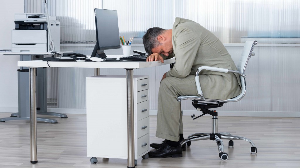 man sitting at office desk, slumped over computer asleep