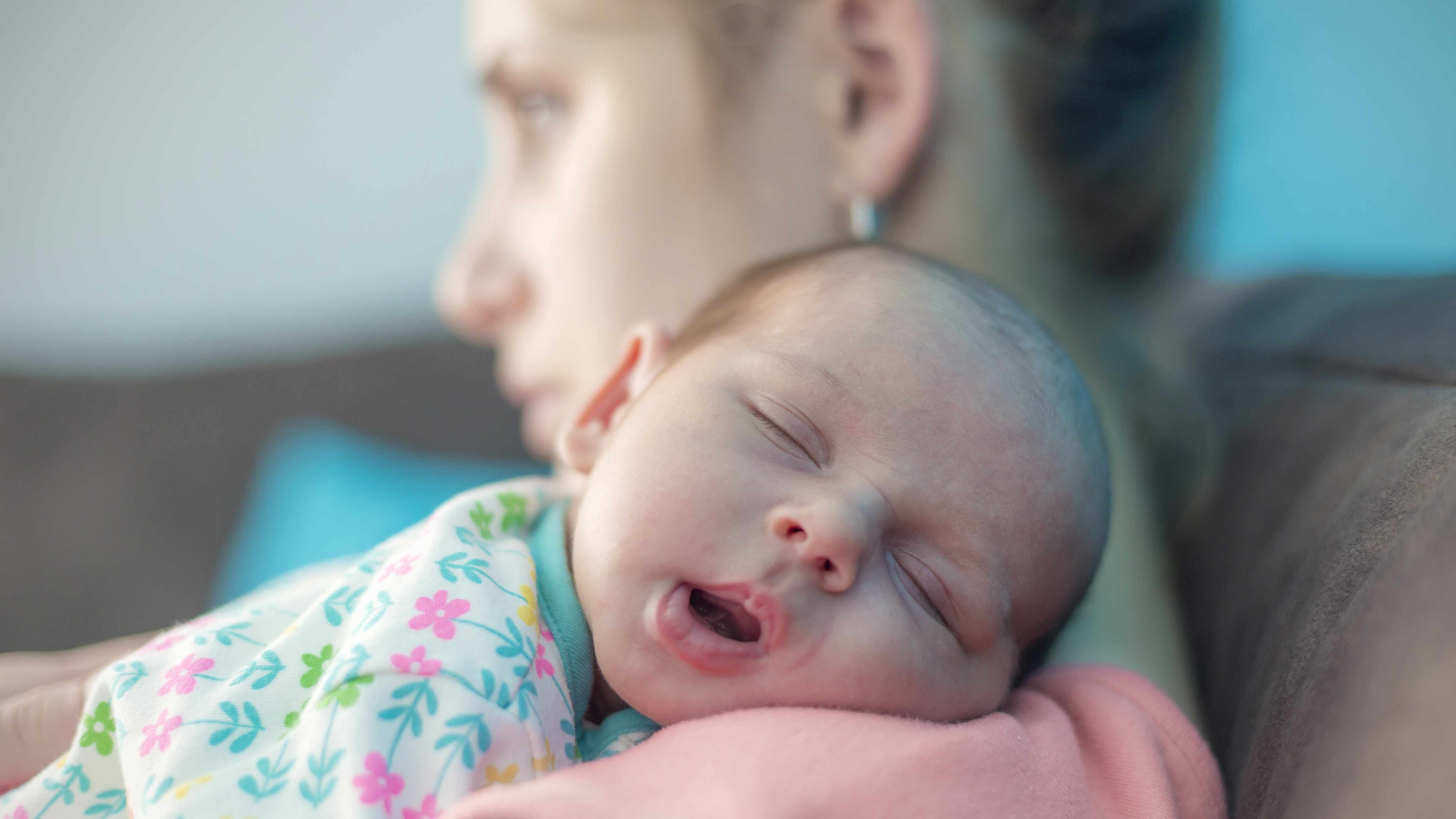 mother holding sleeping baby on shoulder, perhaps representing postpartum depression