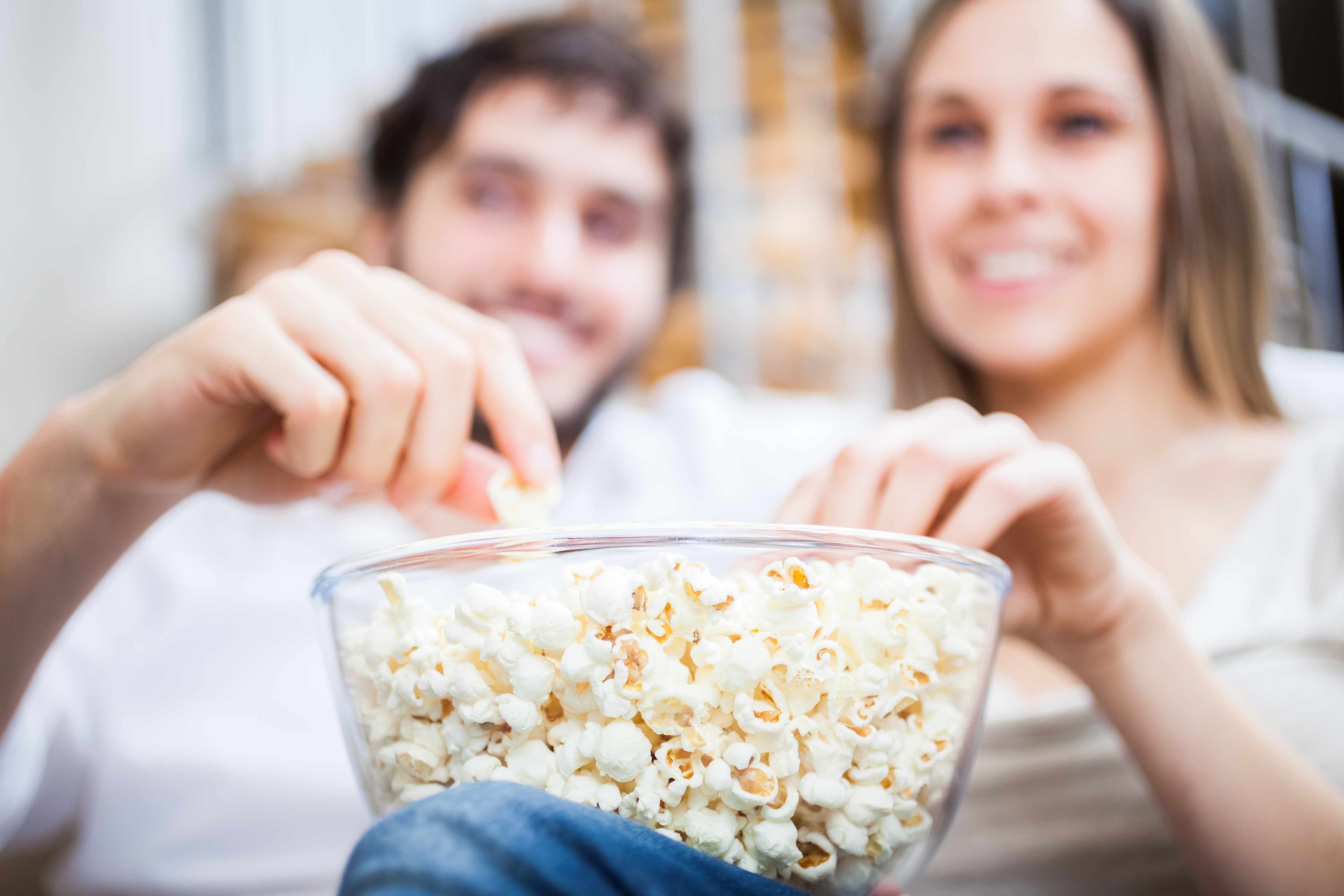 couple enjoying eating a bowl of popcorn