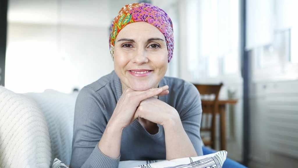 mujer sobreviviente de cáncer con bufanda, sonriendo