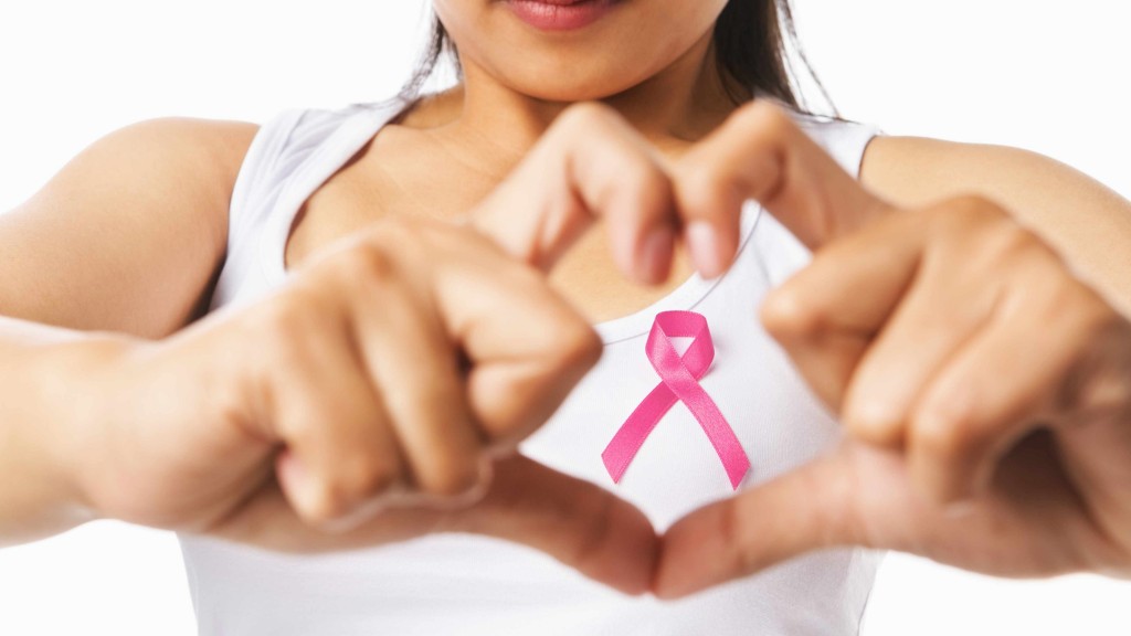 woman in t-shirt making heart symbol with hands and pink ribbon, representing breast health