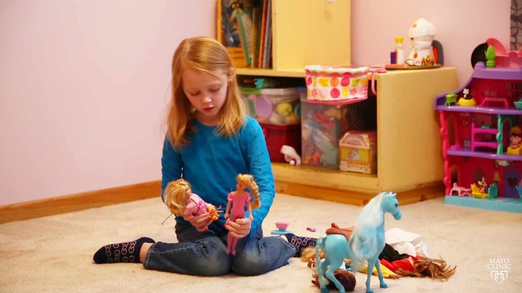 a little girl playing with Barbie dolls