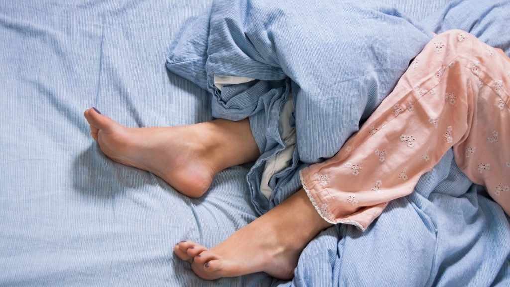 Representación del síndrome de las piernas inquietas con las piernas de una persona acostada en la cama