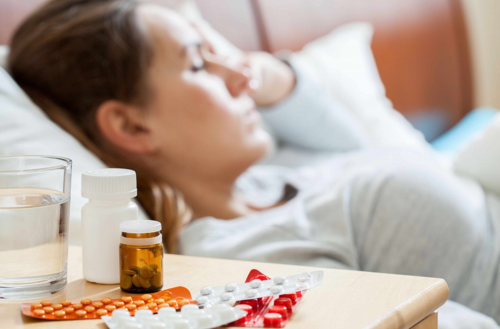 a sleeping woman in bed with medicine pills on a side table