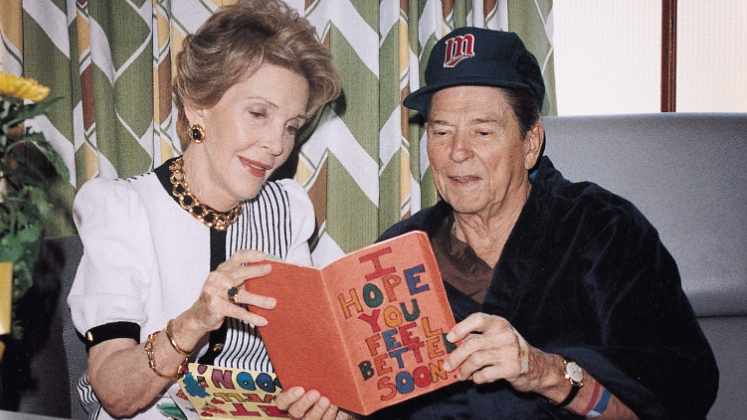Pres. and Mrs. Ronald Reagan in Mayo hospital room looking at greeting cards