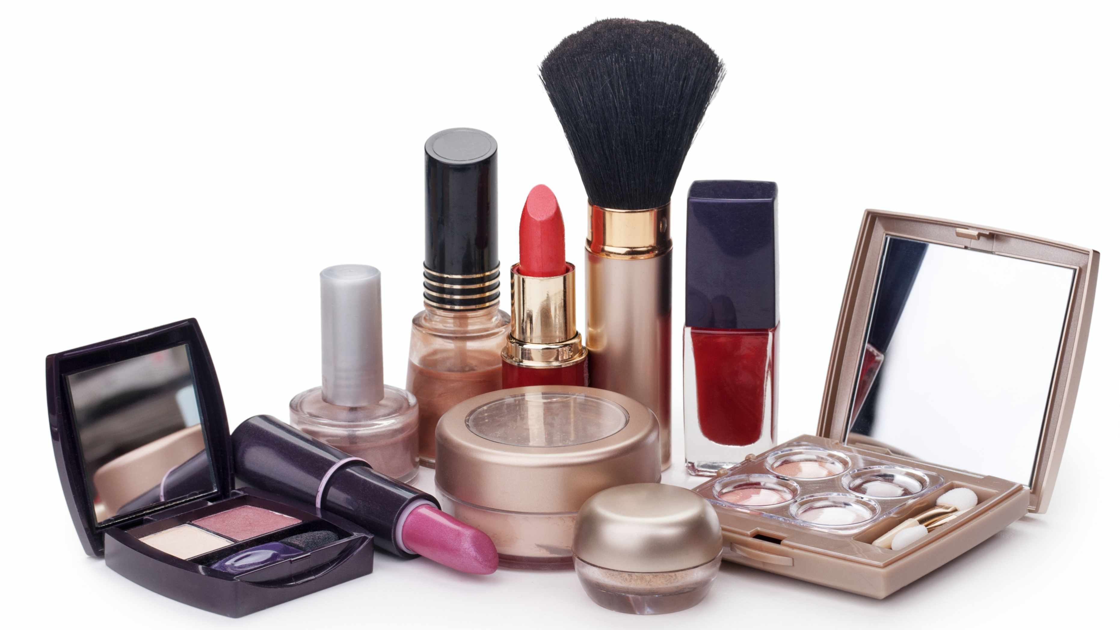 Productos de maquillaje distribuidos sobre una mesa, incluso con lápiz labial y sombra de ojos