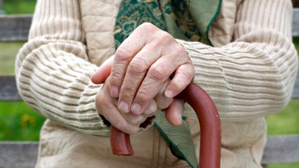 older person sitting with a cane