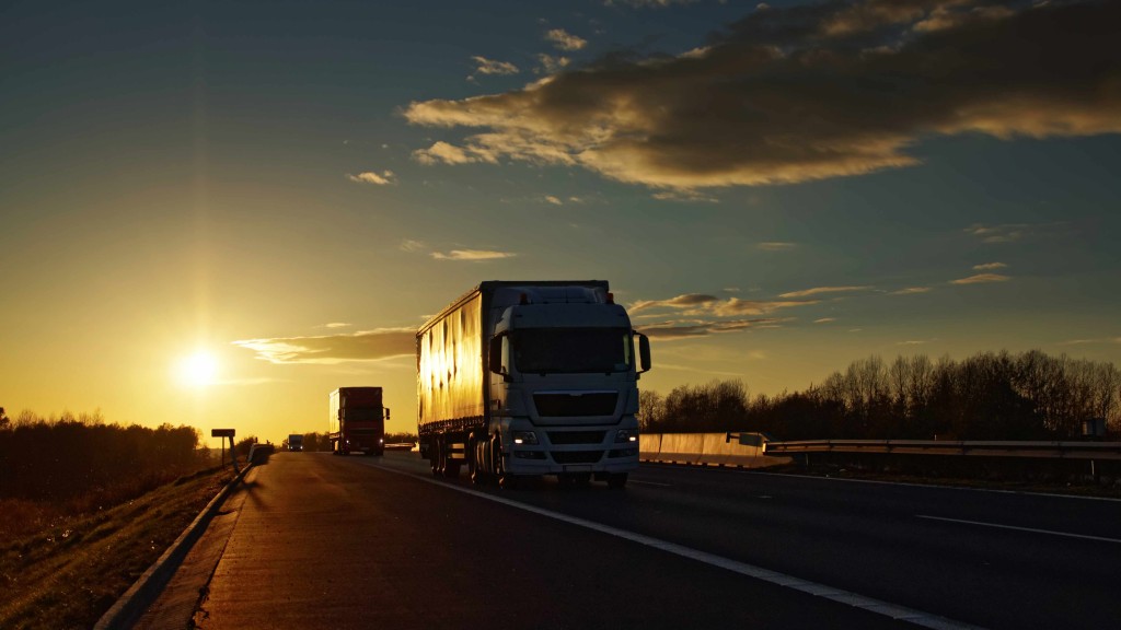 trucks on asphalt highway in a rural landscape at sunset