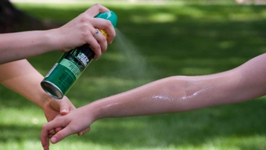person spraying another person's arm with insect repellent