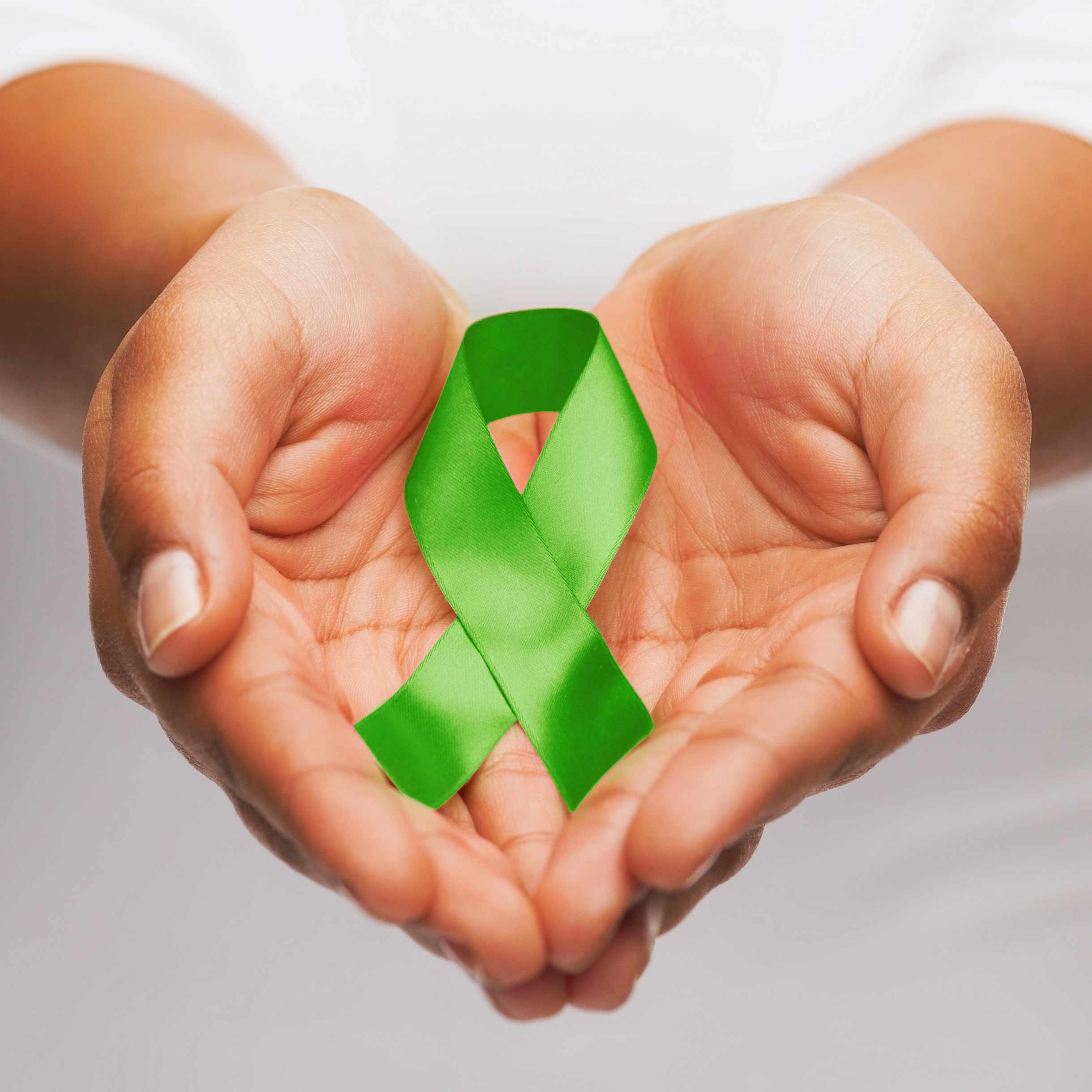 female hands holding green organ transplant awareness ribbon