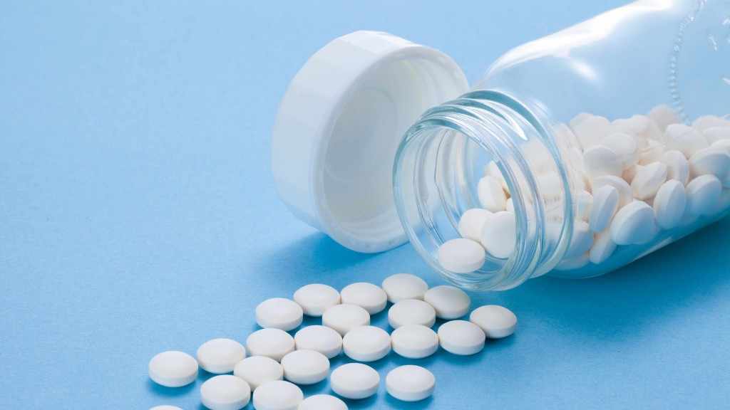 Pequeñas pastillas blancas de aspirina que se escapan de un frasco de cristal