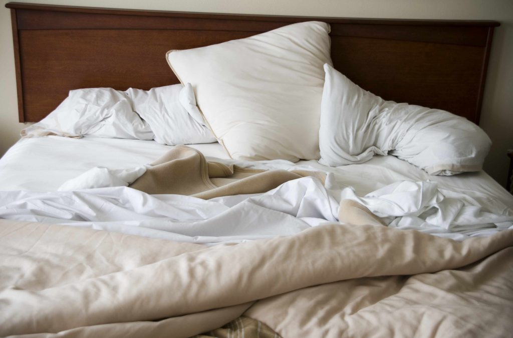 a messy, unmade bed with pillows, blankets and sheets