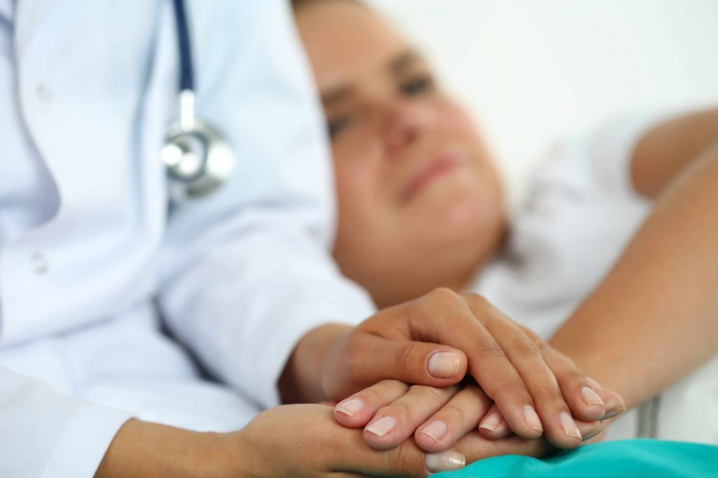 a medical staff person, nurse, doctor comforting a patient, holding their hands