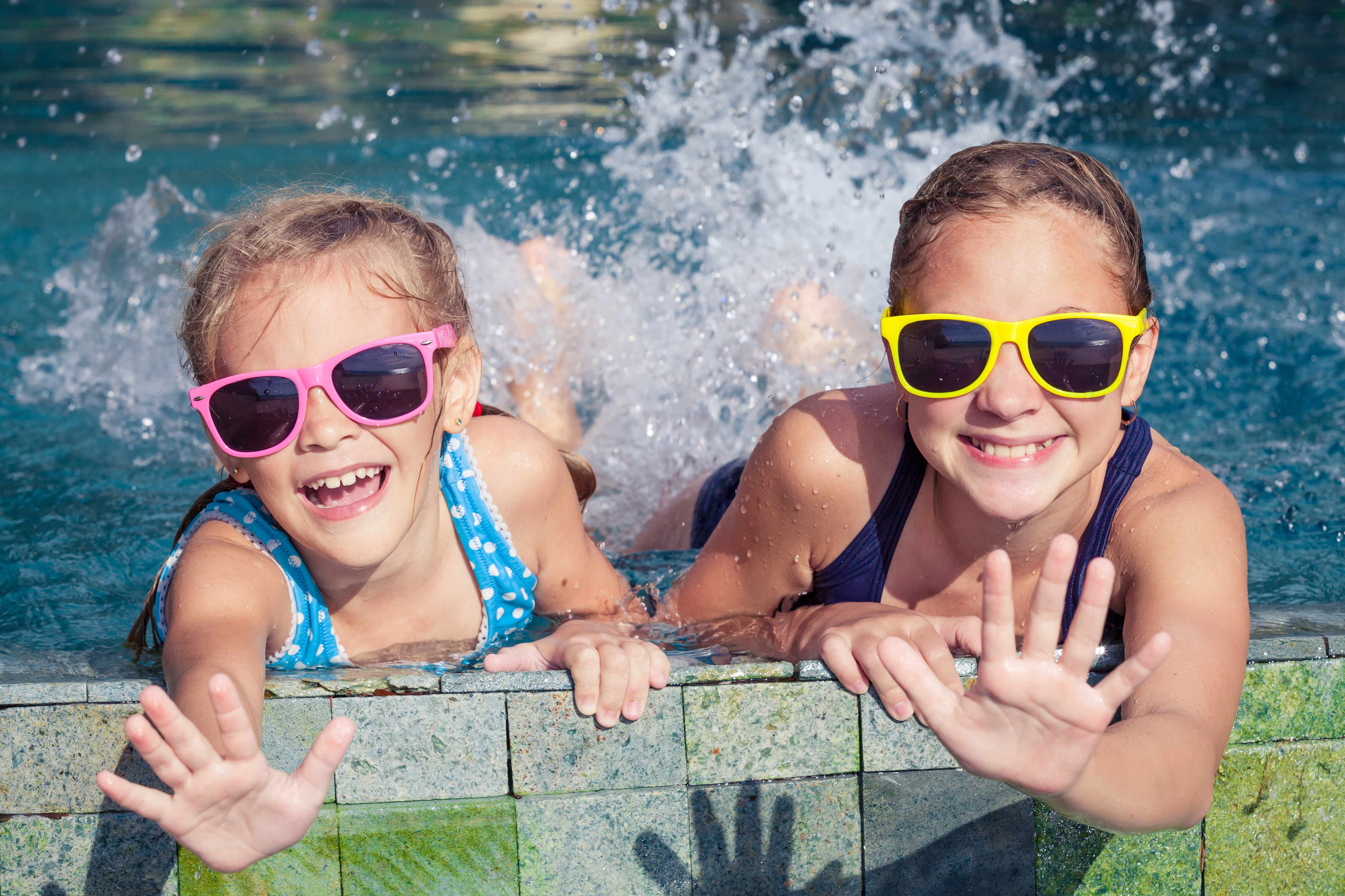 children splashing water in a swimming pool, wearing sun glasses