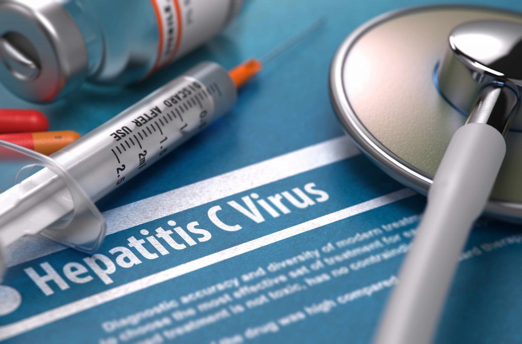 hepatitis C virus written on blue background with pills, syringe and stethoscope
