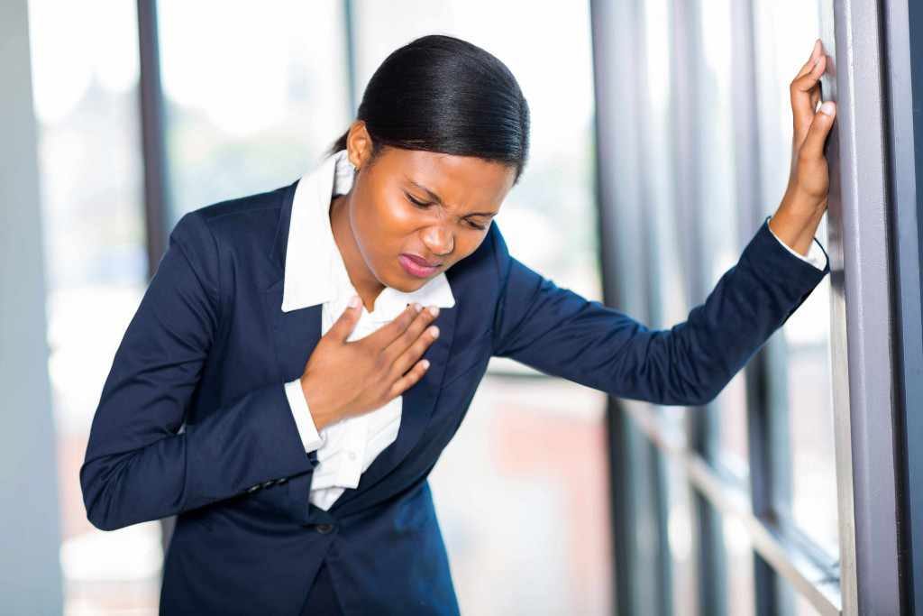 young business woman holding chest appearing to have heart attack