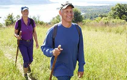 a woman and a man hiking on a grassy hillside, enjoying exercise
