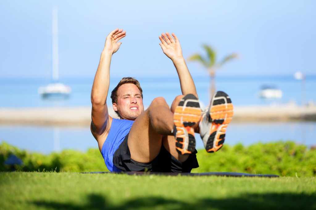 a man doing sit-ups exercising a workout outdoors