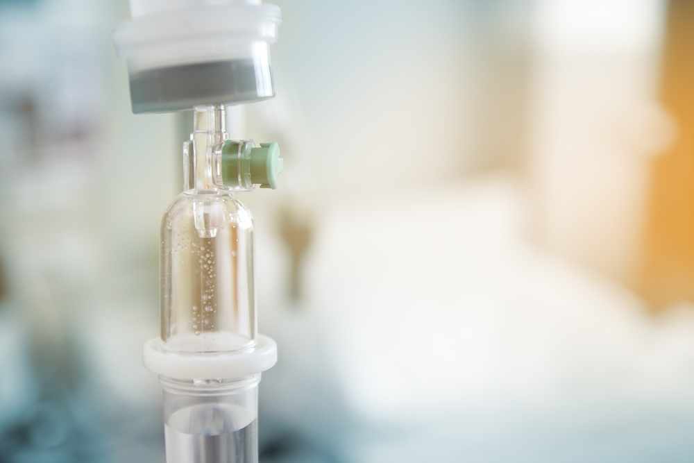 Acercamiento del goteo de una vía intravenosa en un paciente y de una bomba de infusión en el hospital