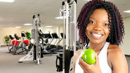 Young woman holding apple at gym, exercise, diet