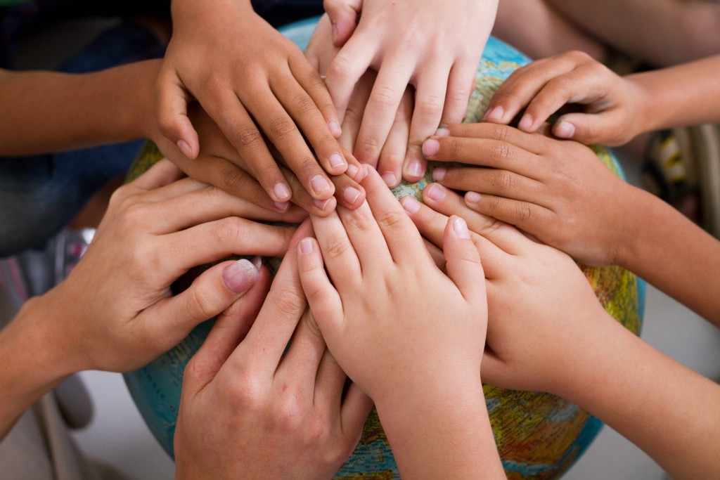 children's hands touching a globe representing world peace, friendships