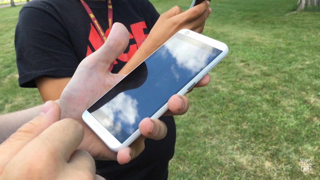 a hand holding a mobile smart phone playing a Pokeman Go game