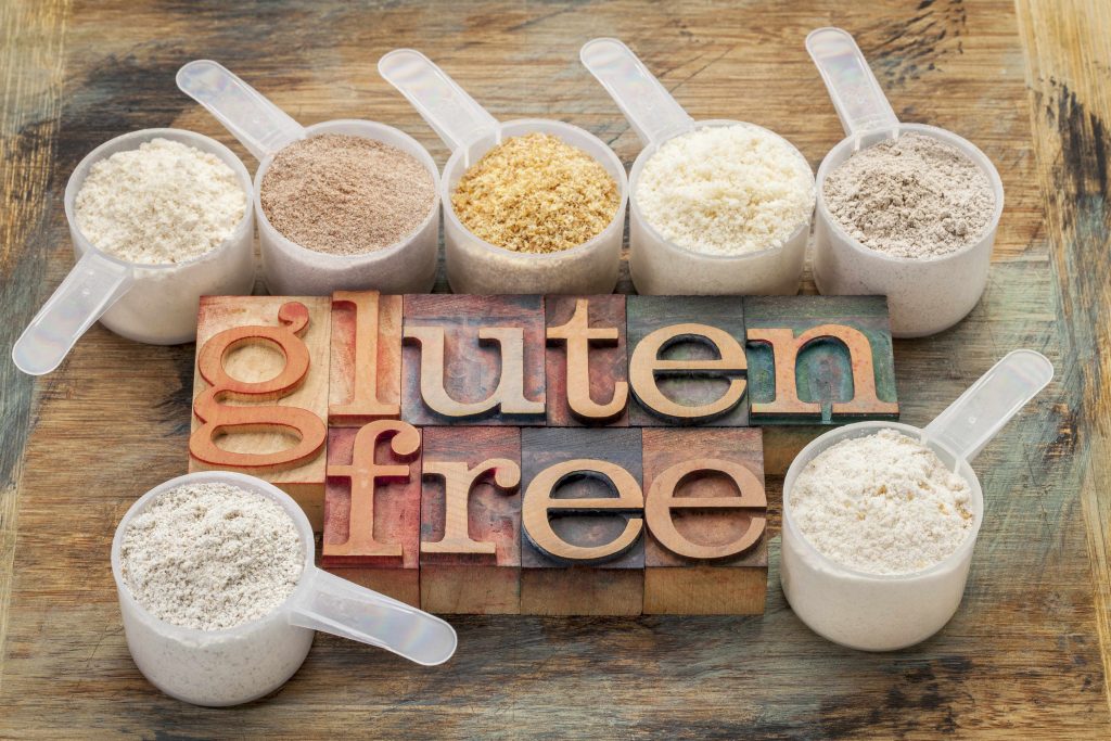 the words gluten free surrounded by scoops filled with various gluten free flours, including almond, coconut, teff, flaxseed meal, rice and buckwheat