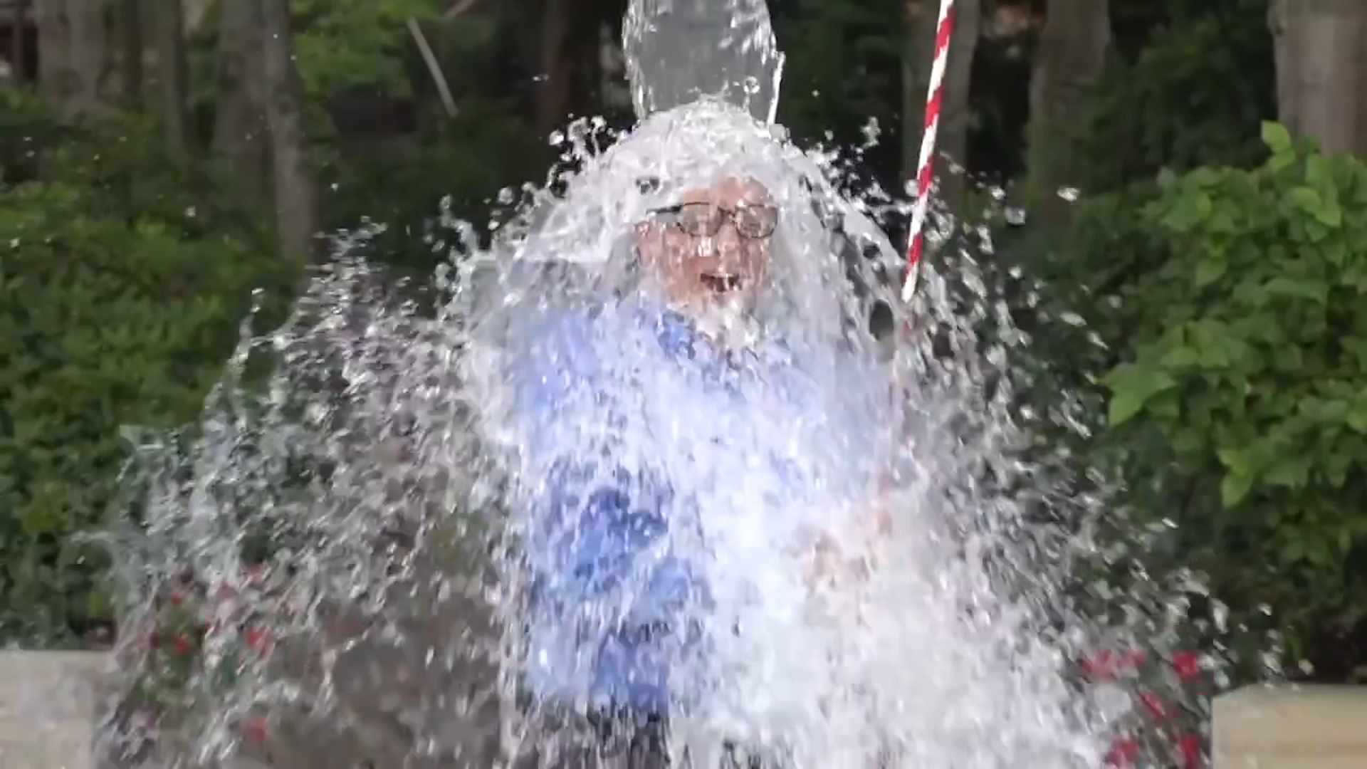 a man in a business suit having ice water dumped on his head for the ALS ice bucket challenge