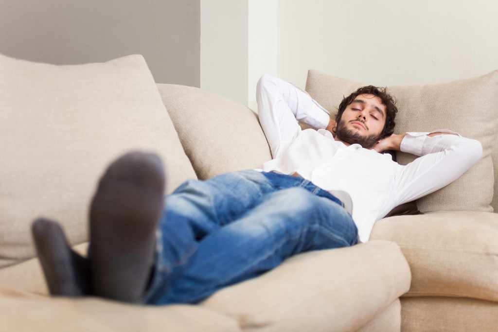 a young man stretched out on a couch, napping