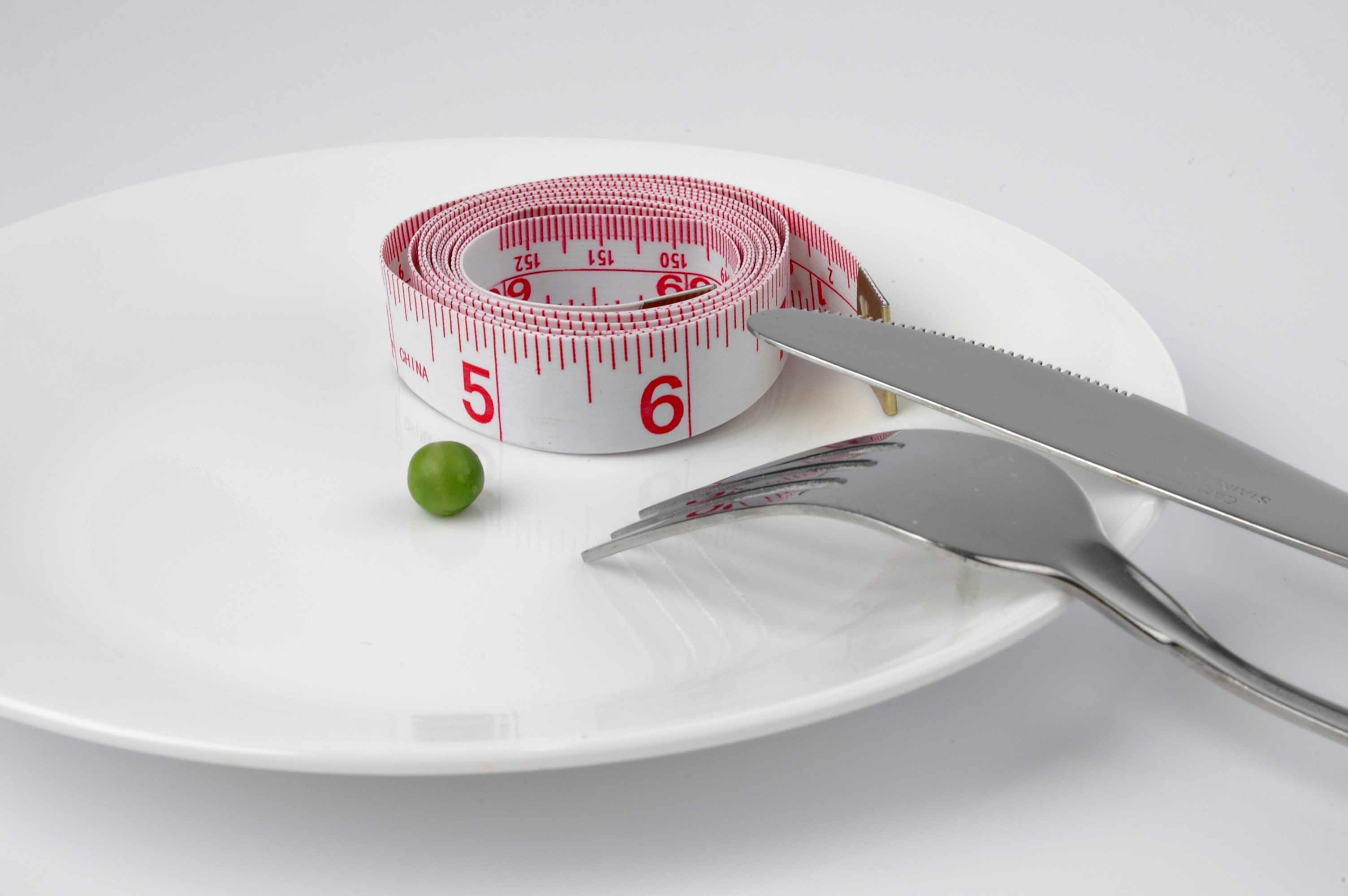 empty plate with tape measure and one pea representing eating disorder
