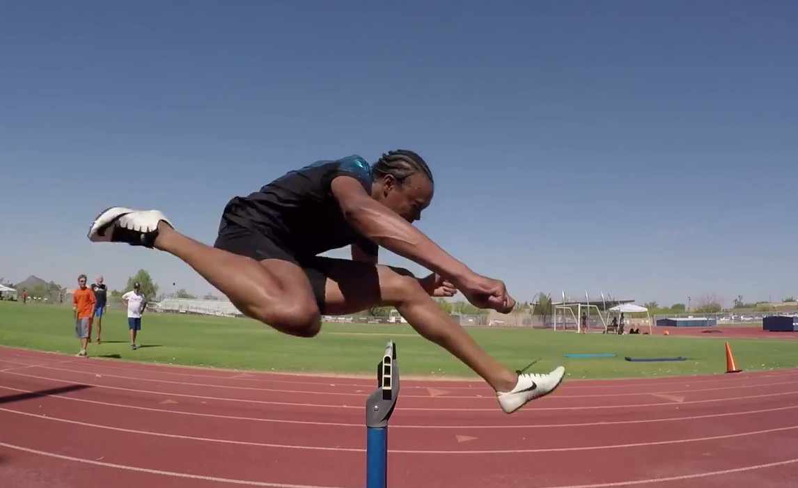 Olympian Aries Merritt jumping a hurdle on a track