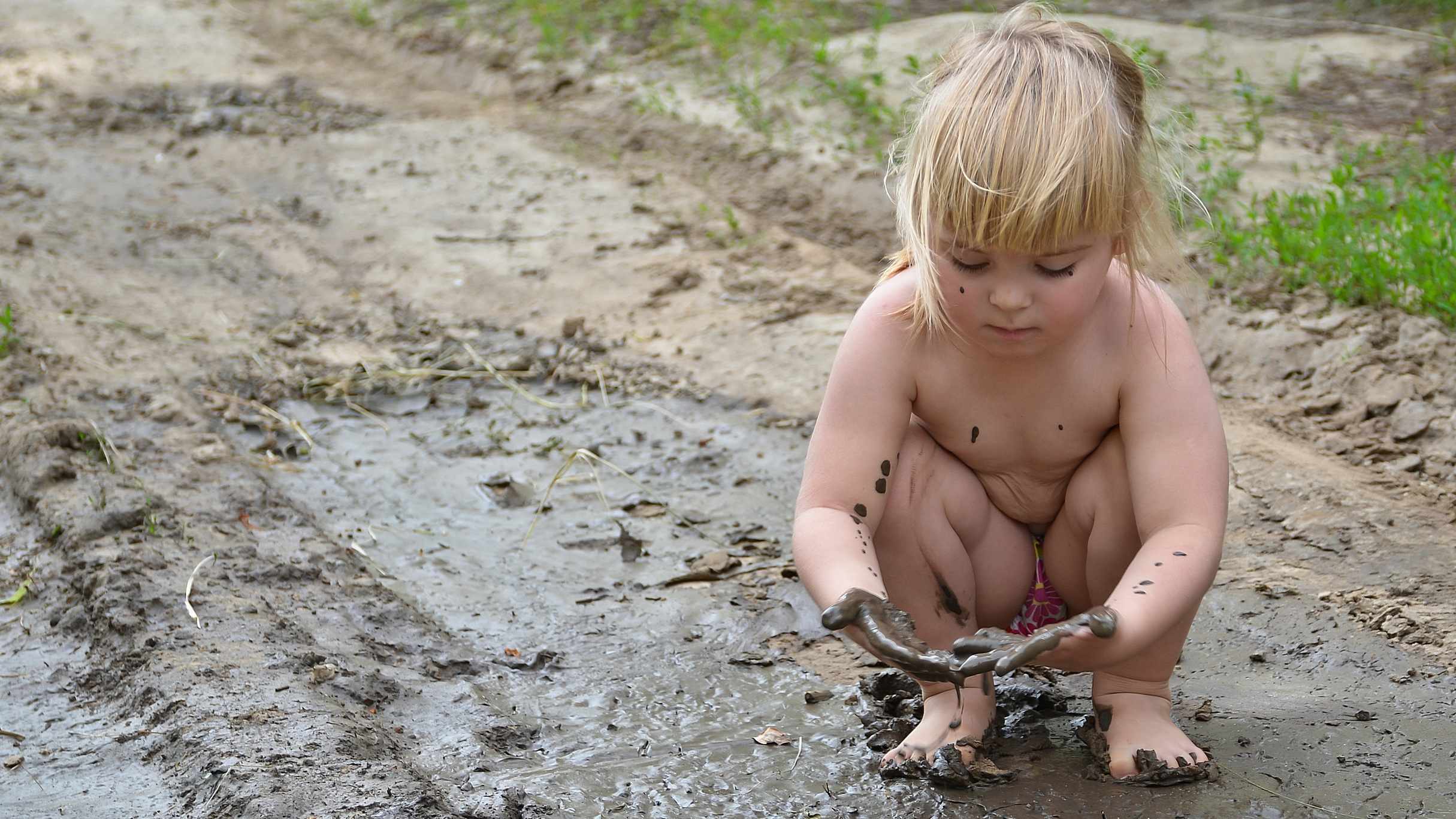 a little girl playing on a dirt road in the mud