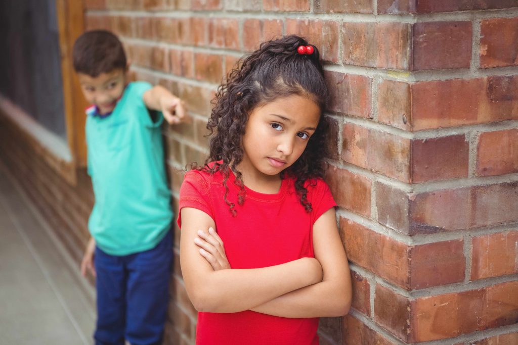 an upset child being teased or bullied by another child at school