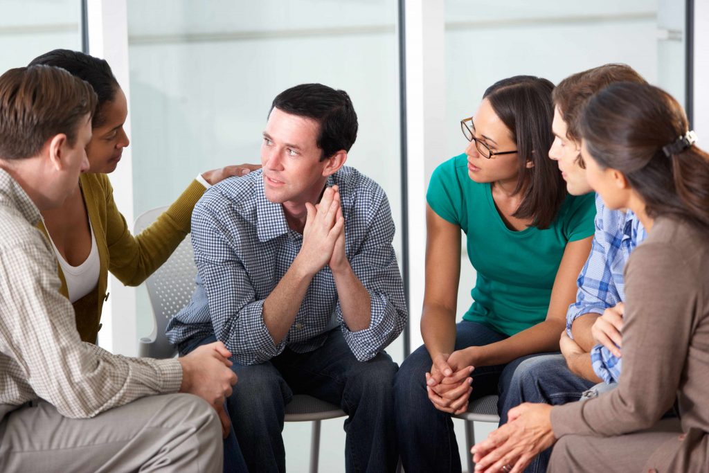 a group of people in a counseling session discussing problems with depression or addiction