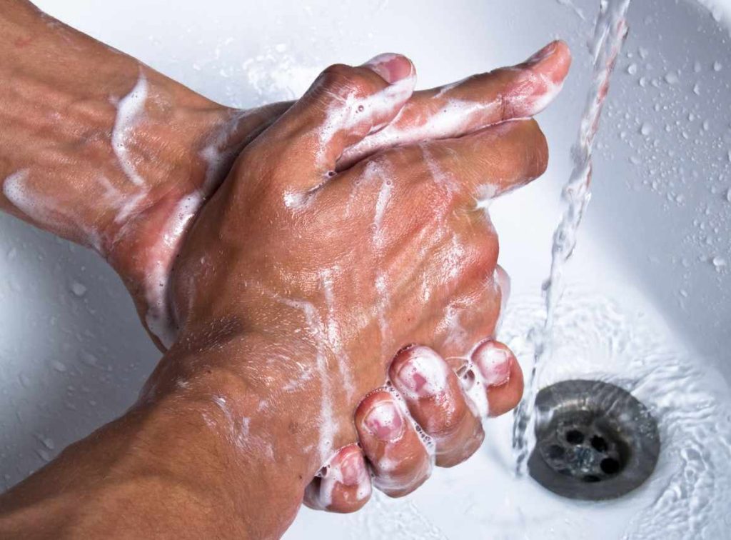 closeup of adult male hands washing with soap and running water in a sink