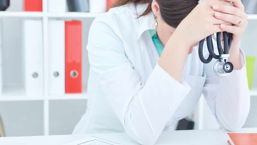 Una joven doctora está estresada y sentada en el escritorio de su oficina