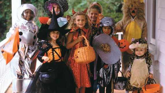 a group of children on a porch, dressed up for Halloween trick-or-treating