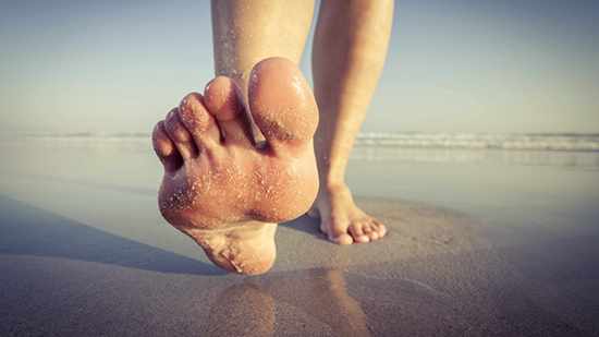 a person's feet walking barefoot on the beach