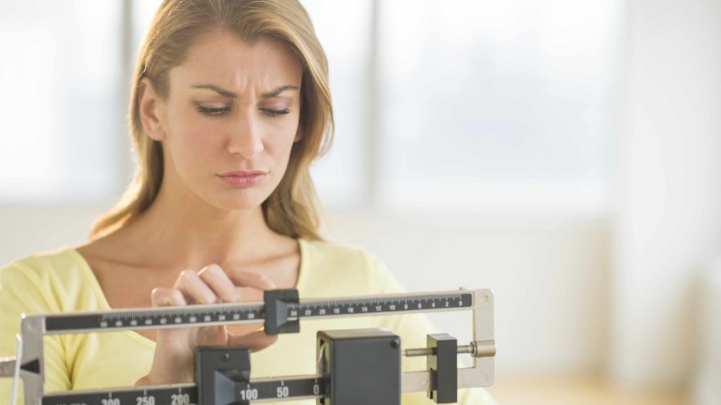 a woman on a weight scale looking disappointed
