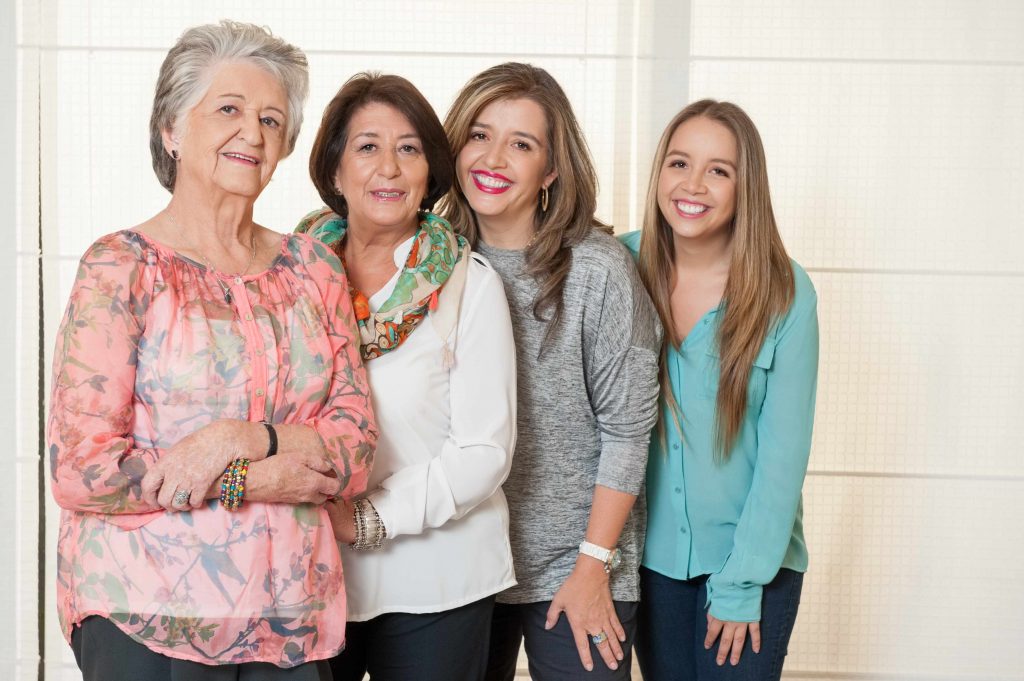 four generations of women, smiling, standing together and leaning against one another
