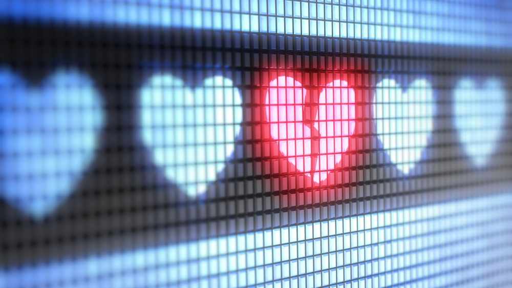 Símbolos en forma de corazón sobre un trasfondo electrónico, con un corazón rojo y roto en el centro